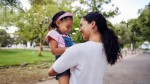 Caregiver holds young smiling child Caregiver holds young smiling child