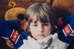 Close-up of a young boy in bugs bunny / USA jersey lying down looking skeptically into the camera