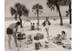 A black and white photograph depicting a 1950s family on a tropical beach.