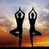 Two people practicing yoga before sunset