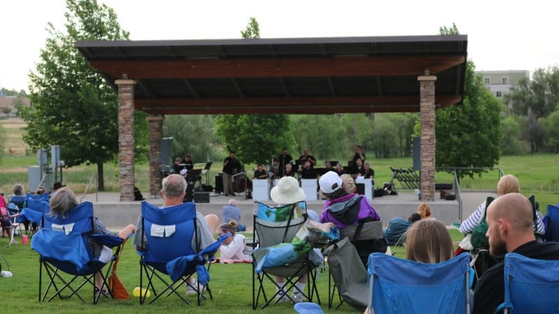 people sitting in lawn chairs on the grass watching a concert at the Family FunPlex outdoor amphitheater