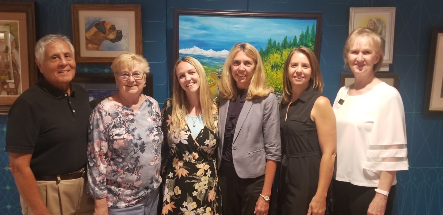 Six adults stand in front of artwork at the Golden Gallery Art Show