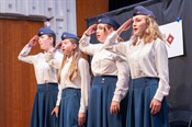 Four girls in WWII-style uniforms salute as part of a National History Day Performance Showcase