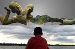 Composite. Above, bronze sculpture reclines, missing parts of torso and waist. Below, monk looks out at expanse of water. Composite. Above, bronze sculpture reclines, missing parts of torso and waist. Below, monk looks out at expanse of water.