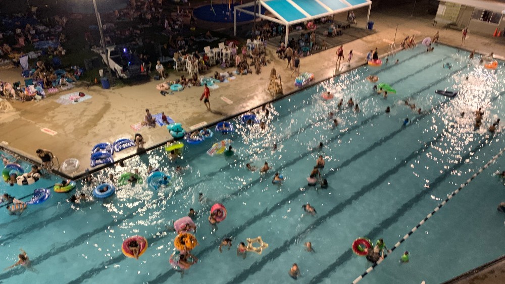 youth and adult float at Centennial Pool while watching a movie