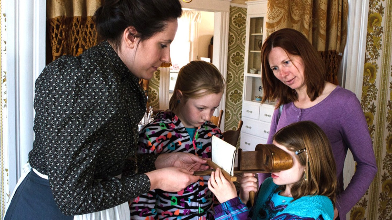 Adult showing a child a stereoscope while another child and an adult look on