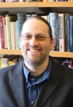 man with beard in front of books