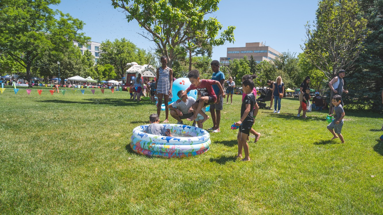 Young boy jumps in a wading pool at Lincoln Park during Family Field Day