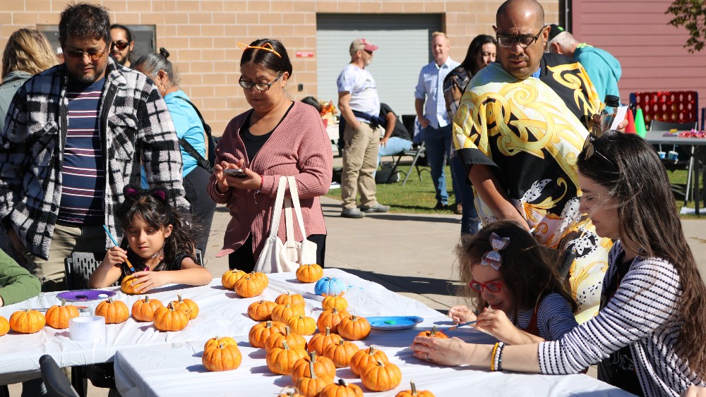 Families paint pumpkins at the fall carnival and resource fair
