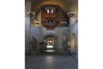 A room with several arches and figural statues in the corners with an organ musical instrument in the center.