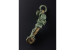 A brooch with green patina features red and yellow geometric enamel decorations.