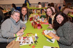 Four women sit at a table with a collection of paper crafts and supplies. Four women sit at a table with a collection of paper crafts and supplies.