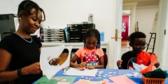 Woman and two children smiling and working on craft project