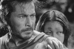 In black and white, a man drenched in sweat glares to the right. A woman peers the same direction from behind his shoulder.