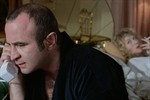 Bob Hoskins talking on the phone as he sits on a bed shared with Helen Mirren