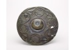 A circular bronze shield boss features a raised center and a swirling decoration of circular vegetal tendrils and two birds’ heads around the edge. A circular bronze shield boss features a raised center and a swirling decoration of circular vegetal tendrils and two birds’ heads around the edge.