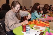 A young white woman smiling while making a paper craft. 
