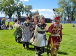 Dancers in traditional Haudenosaunee dress with arms linked dance outdoors on a sunny day Dancers in traditional Haudenosaunee dress with arms linked dance outdoors on a sunny day